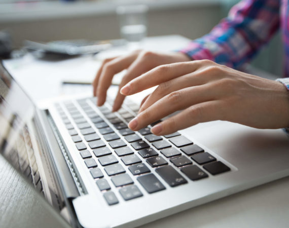Vista recortada das mãos da pessoa digitando no computador portátil, buscando o que é SEO