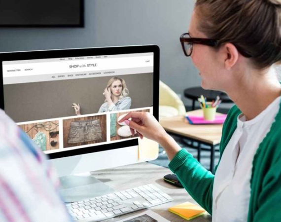 mulher conversando sobre como otimizar as imagens em seu site, em seu computador, com um pessoa, que aparece de costas, no canto da imagem.