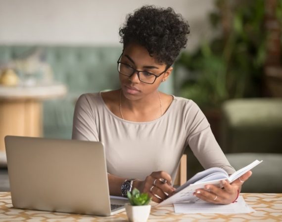 Gramática no SEO sendo analisada por mulher que fazer anotações.